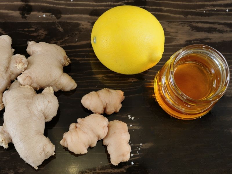 na drvenom stolu stoji limun, teglica meda i nekoliko djubira